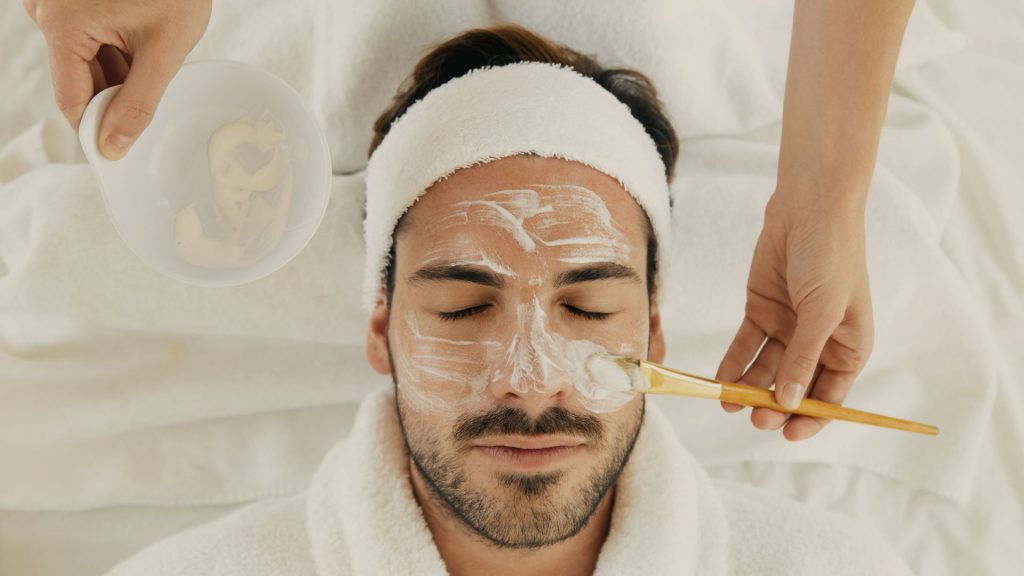 Man receiving a facial with towel on head